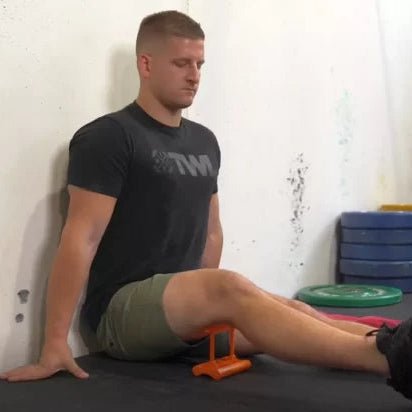 Man performing hamstring stretching routine at home with Mobilization Magic™ tool in a seated position.