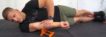 User demonstrating supine position fascia release for elbow and triceps muscle tension.